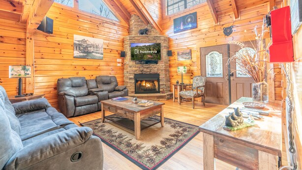 A cozy log cabin interior with a fireplace, leather furniture, and wooden walls. - Comfort Cabin Bearway To Heaven - w Private Hot Tub (Pigeon Forge)