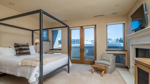Een slaapkamer met een hemelbed, een stoel, een televisie en een open haard.