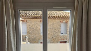 Eine Glastür führt zu einer Terrasse mit Steinmauer, einem kleinen Tisch und einem Stuhl.