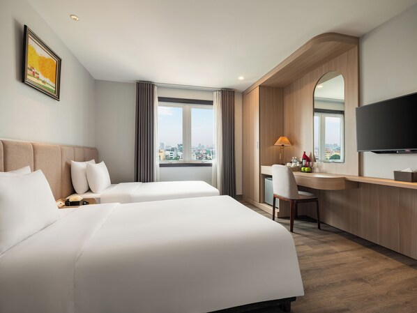 A hotel room with two beds, a desk, a chair, a TV, and a window with a city view. - Minasi Premium Hotel (Hanoi)