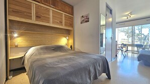 Quarto moderno com cabeceira de madeira, uma cama grande e vista para uma varanda externa.