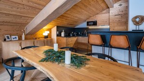 Une cuisine chaleureuse avec des poutres en bois, une table à manger avec des chaises et un four à micro-ondes placé au-dessus du comptoir.