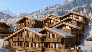 Un chalet en bois à plusieurs étages, doté de balcons, de murs en pierre et surplombant un paysage enneigé.