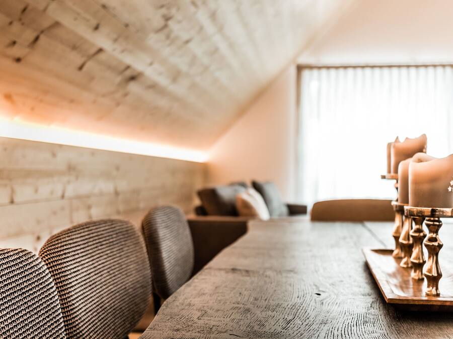 A dining table with candles, a brick wall, and a window with blinds.