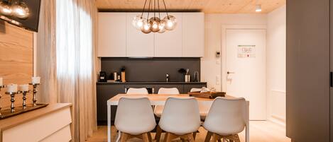 Una cocina moderna con comedor, techo de madera y una lámpara de araña.