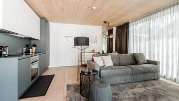 Un espacio habitable moderno con cocina, sofá gris y una mesa redonda.