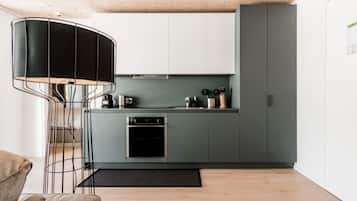 Una cocina moderna con armarios grises, horno integrado y cafetera.