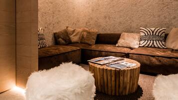 A cozy corner with a cushioned seating area, a round wooden table, and fluffy white poufs.