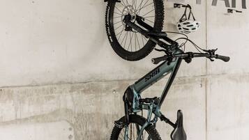 A bicycle parked in a garage with a wall that reads 'THE BASE ANDERMATT BIKE PARK.'