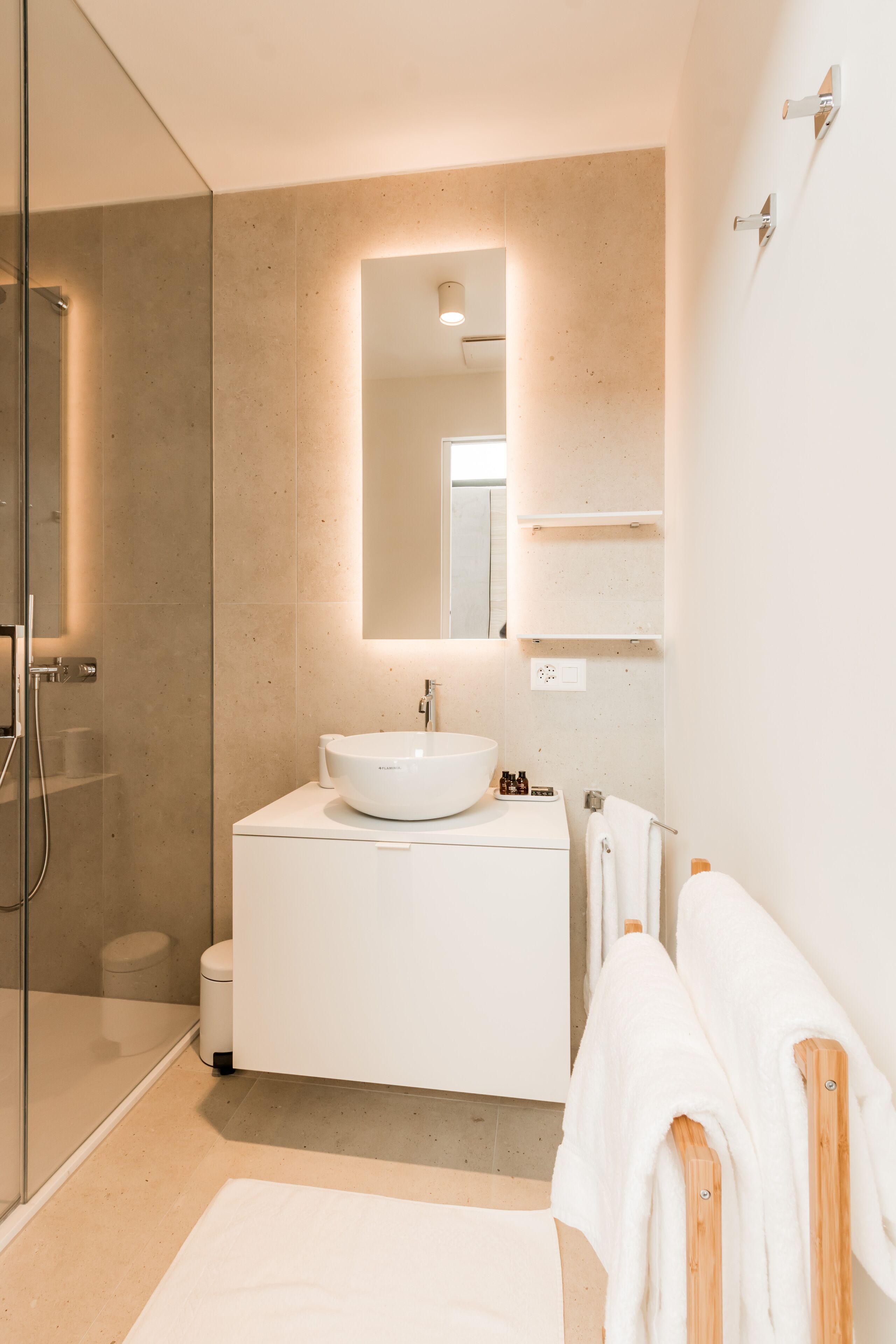 A modern bathroom with a glass shower enclosure, a white sink, and a large mirror.