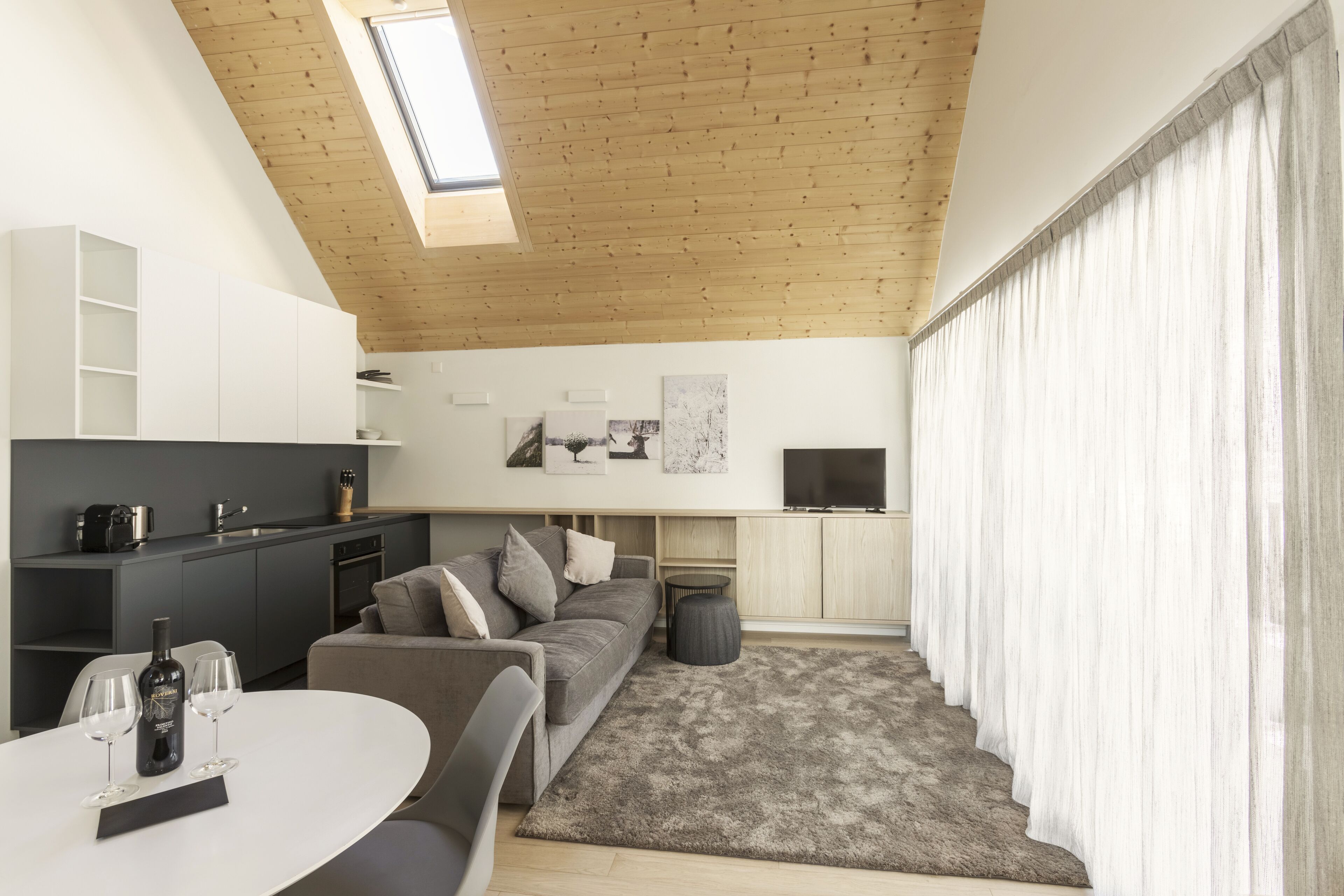 A modern living room with a grey sofa, a round coffee table, and a TV on the wall.