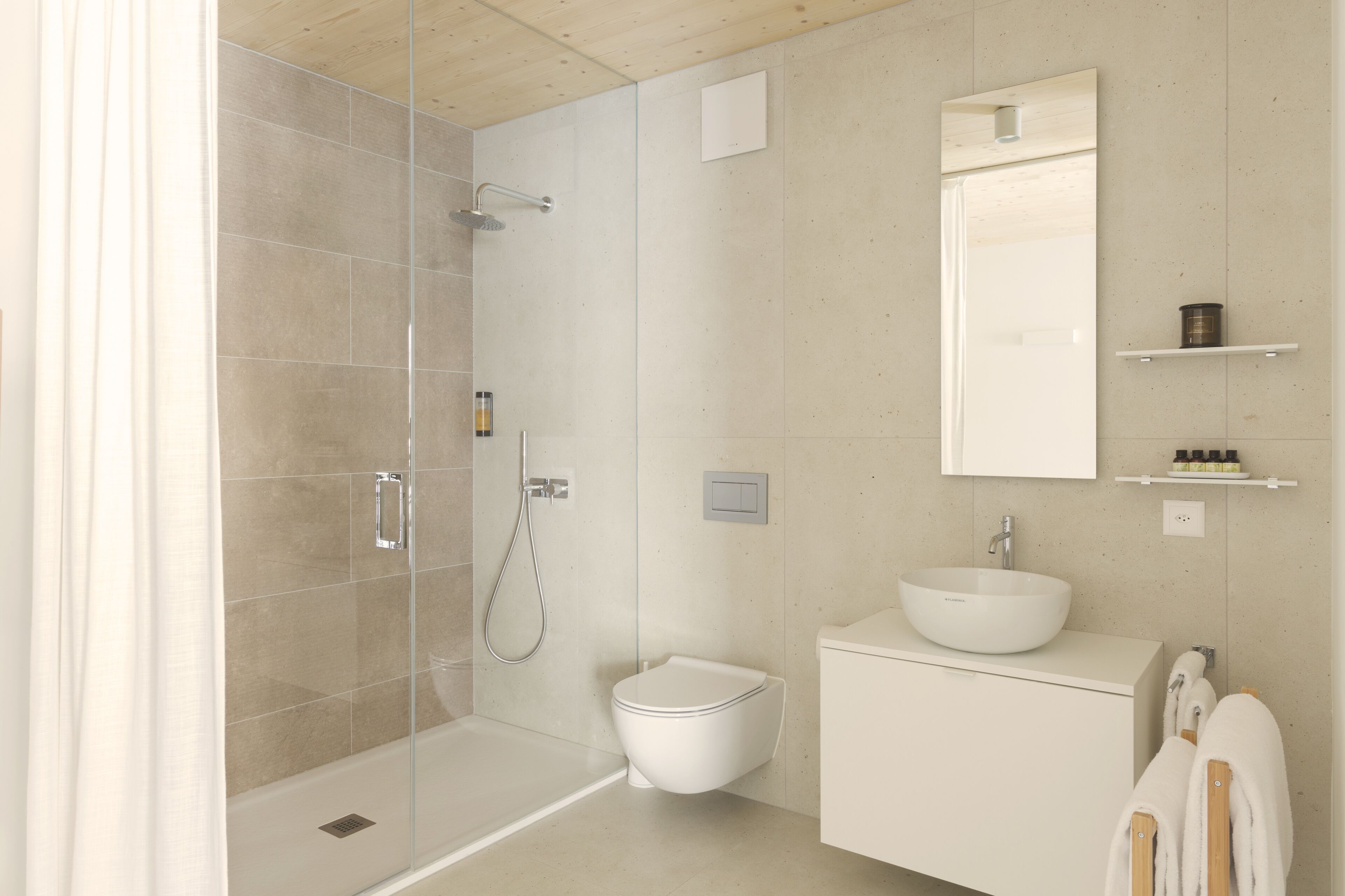 A modern bathroom with a glass-enclosed shower, a white toilet, and a sink with a mirror above it.