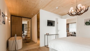 A modern bedroom with a large bed, wooden ceiling, and a chandelier. - THE BASE  (Andermatt)