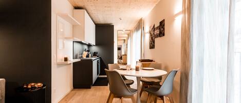 A modern kitchen with a dining area, wooden flooring, and a view of the adjacent living space.