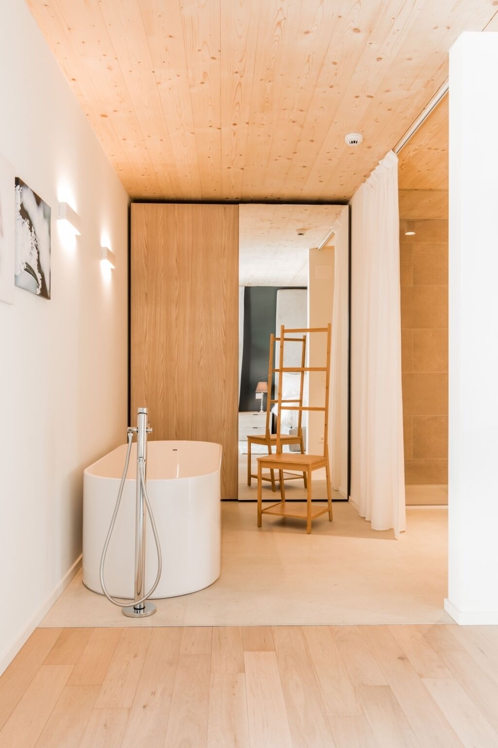 Un baño moderno con techo de madera, una bañera, ducha y una silla de madera.
