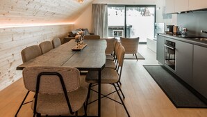 A modern kitchen with a large island, wooden ceiling, and a view of the outdoors. - THE BASE  (Andermatt)