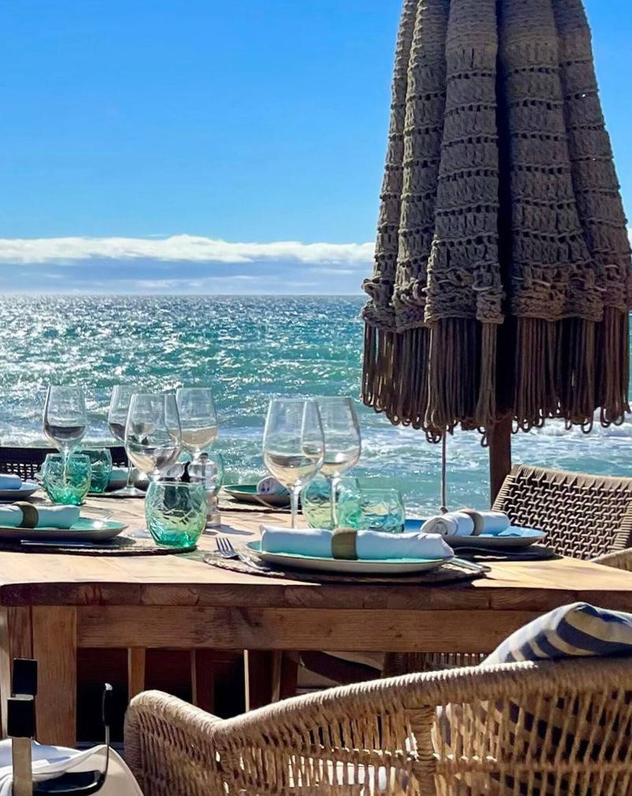 Een eettafel gedekt met glazen en borden, met uitzicht op een schilderachtig zeegezicht.