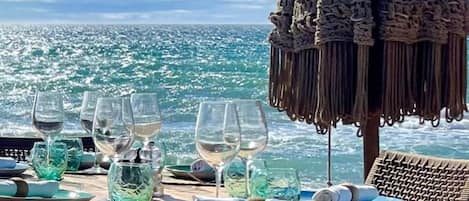 A dining table set with glasses and plates, overlooking a scenic ocean view.
