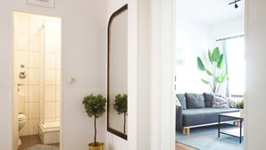 Een moderne badkamer met een douche, toilet en wastafel. Er staat een potplant en hangt een spiegel aan de muur.