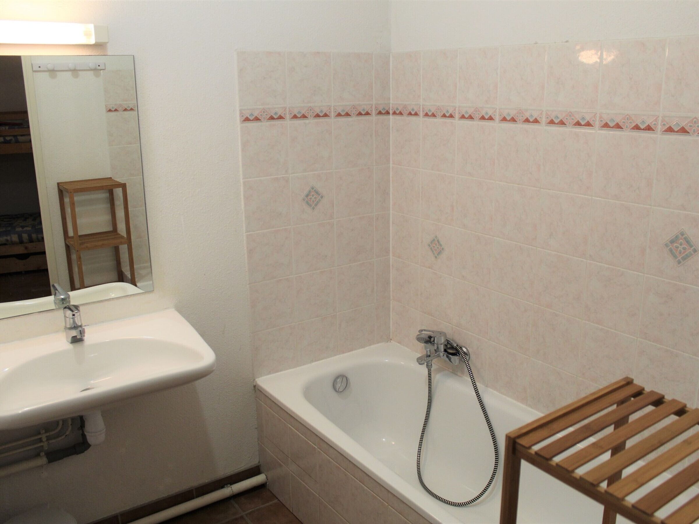 Un bagno con lavandino, specchio, vasca e ripiano in legno.