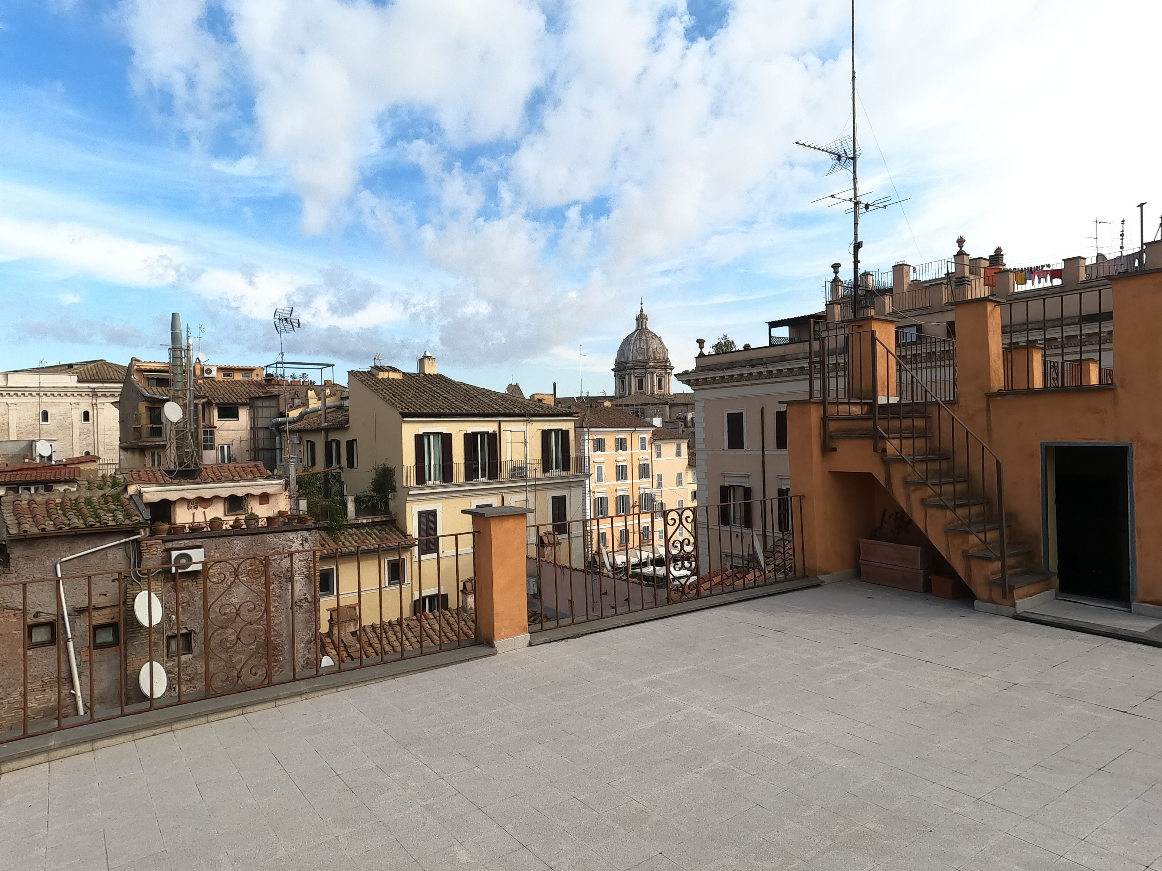 A rooftop terrace with a view of historic buildings and a dome structure in the background.