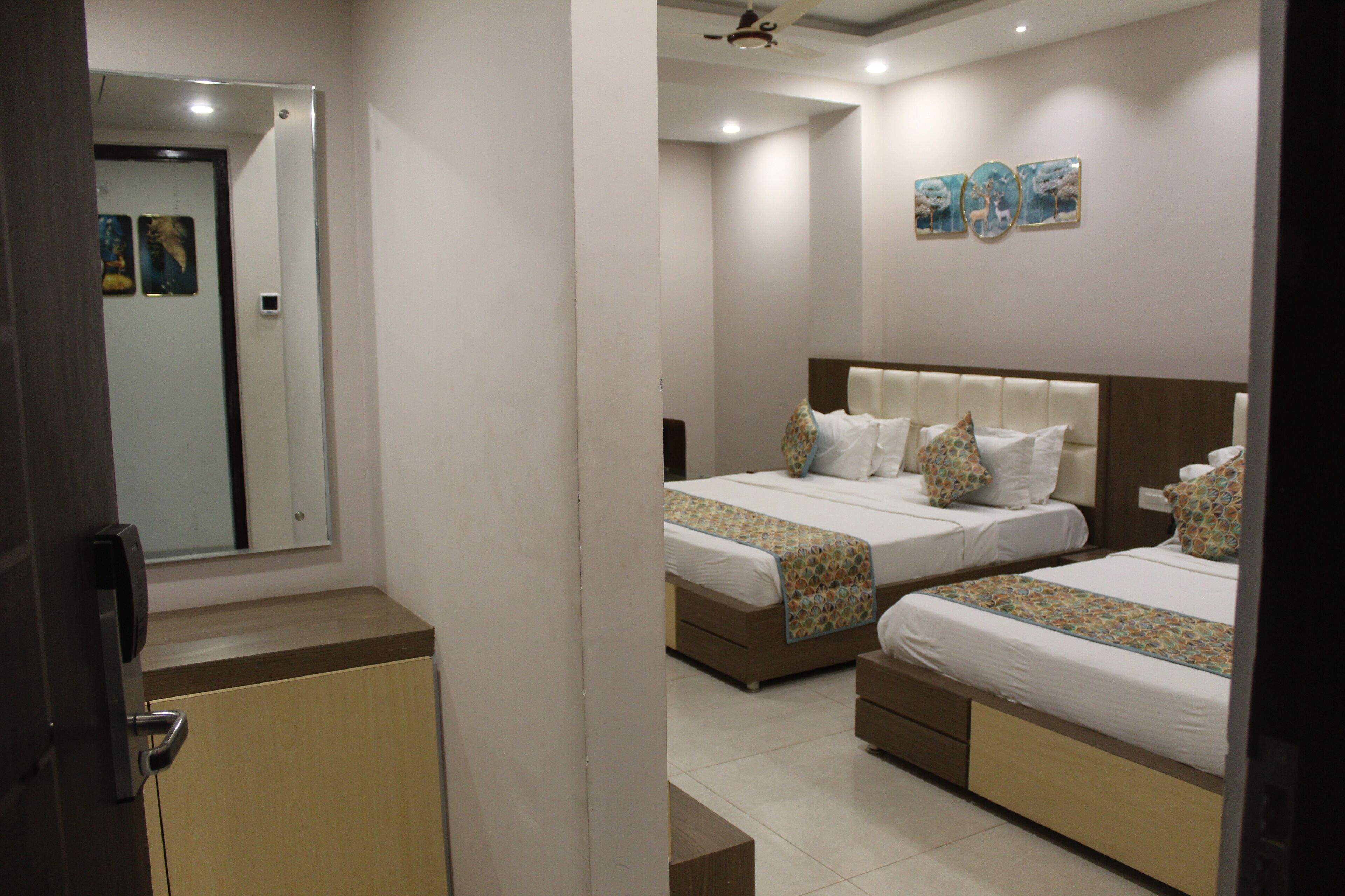 A hotel room with two beds, a mirror, and artwork on the wall.