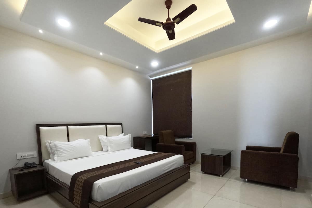 Quarto moderno com uma cama grande, um ventilador de teto, mesa de cabeceira, cadeira e janela com persianas.
