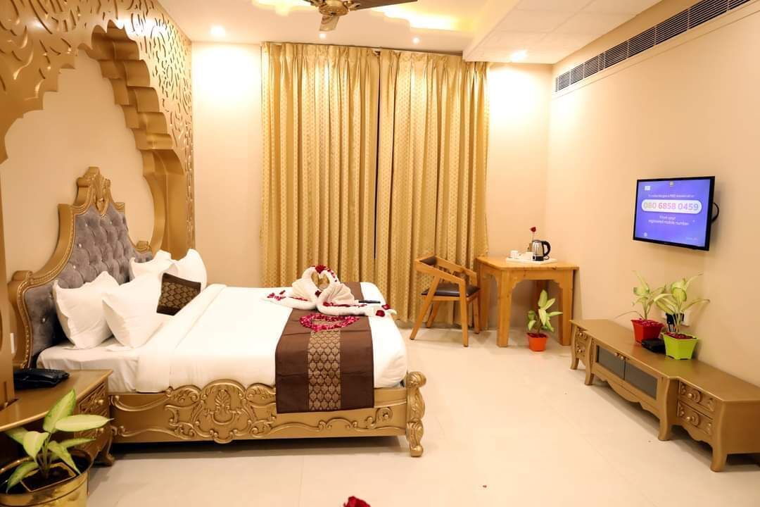 Ein Hotelzimmer mit einem großen Bett, einem Schreibtisch, einem Sessel und einem Fernseher.
