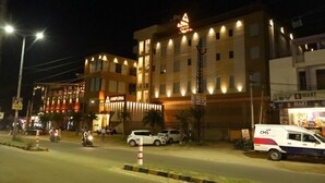 Un hotel de varios pisos con un llamativo letrero 'ANIPURNA', una tienda 'B MART' y un camión de reparto 'CMS' estacionado frente.