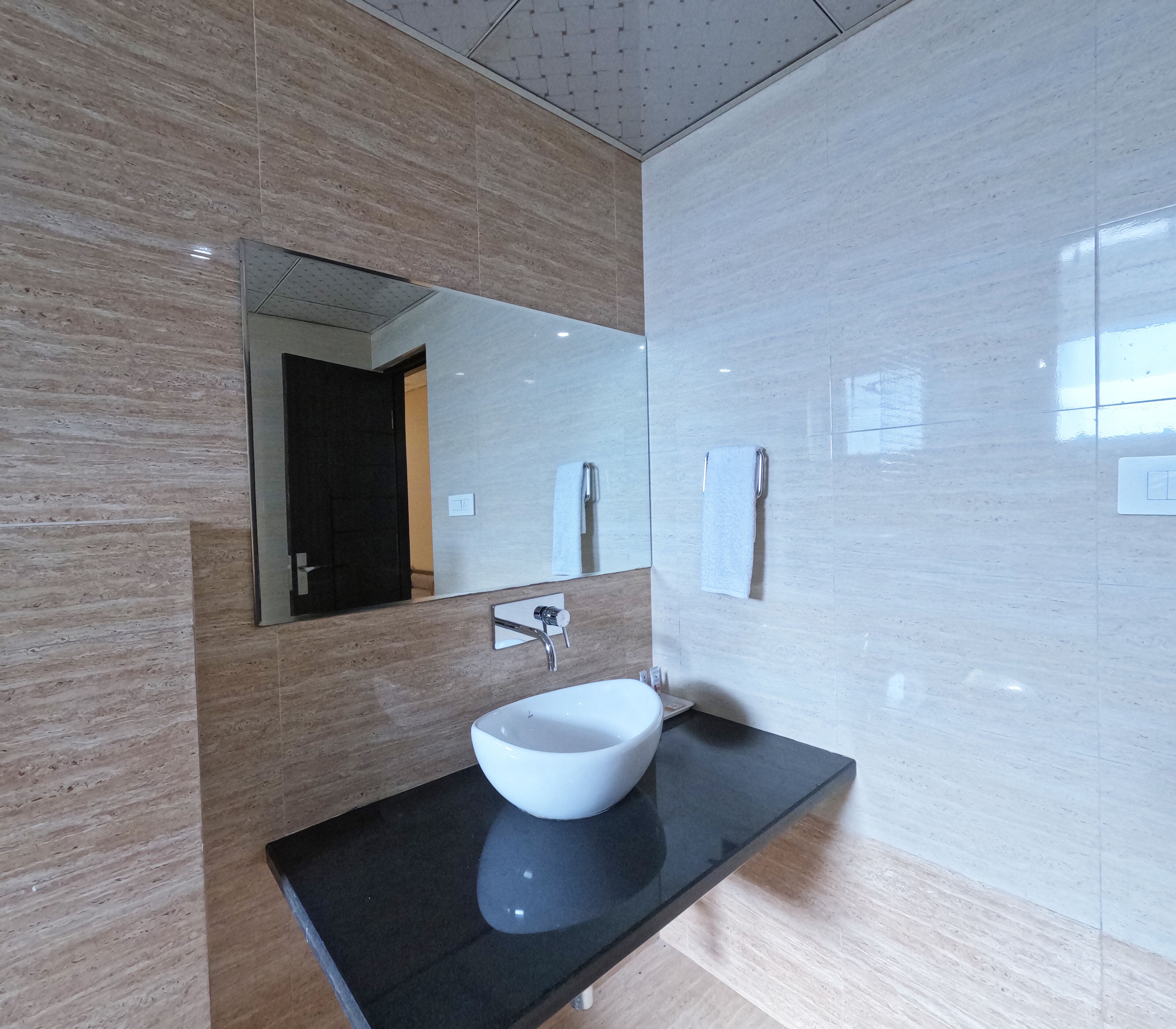A modern bathroom with a large mirror, a white sink, and a black countertop.
