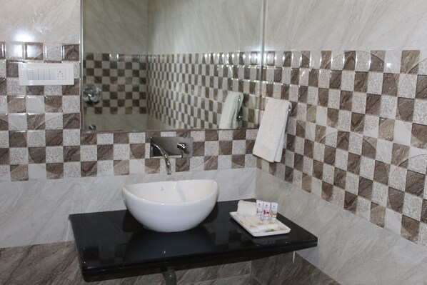 A bathroom with a white sink, black countertop, and checkered tile walls. - Hotel Annpurna Regency (Sikar)
