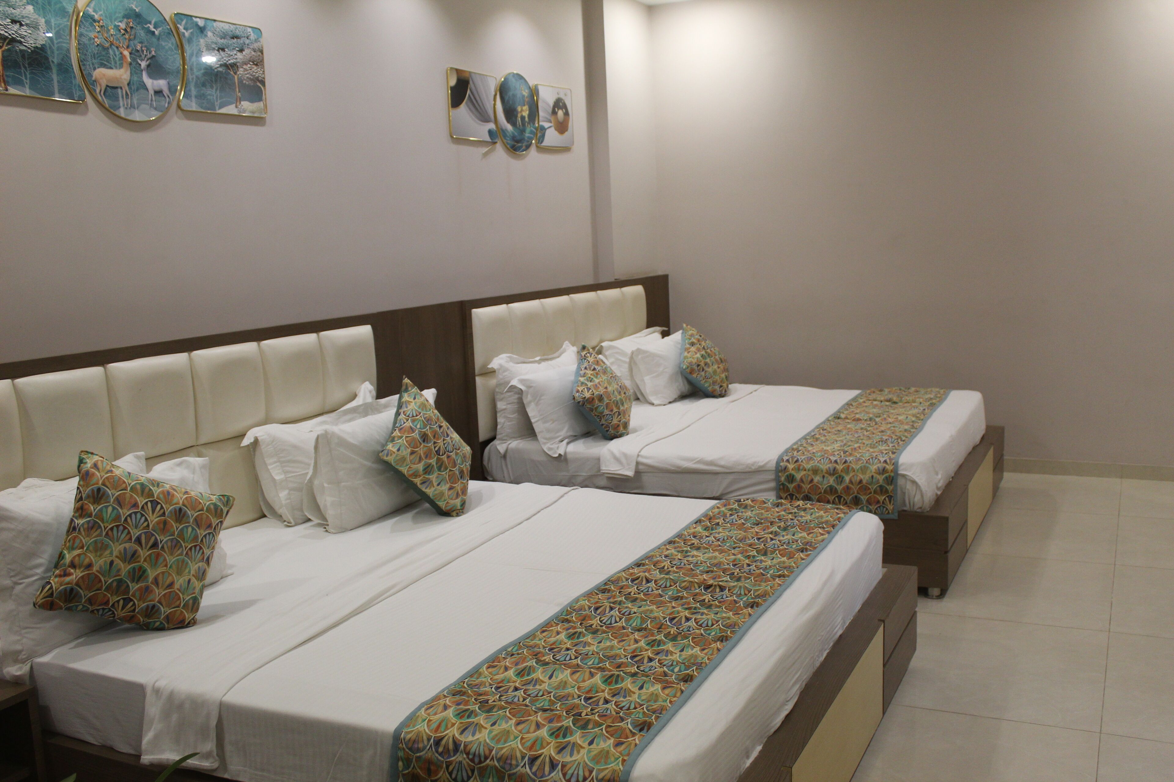 A hotel room with two beds, each with white linens and patterned bedspreads.