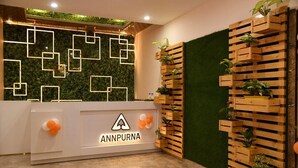 Un mostrador de recepción con un logotipo, un diseño mural geométrico y un jardín vertical.