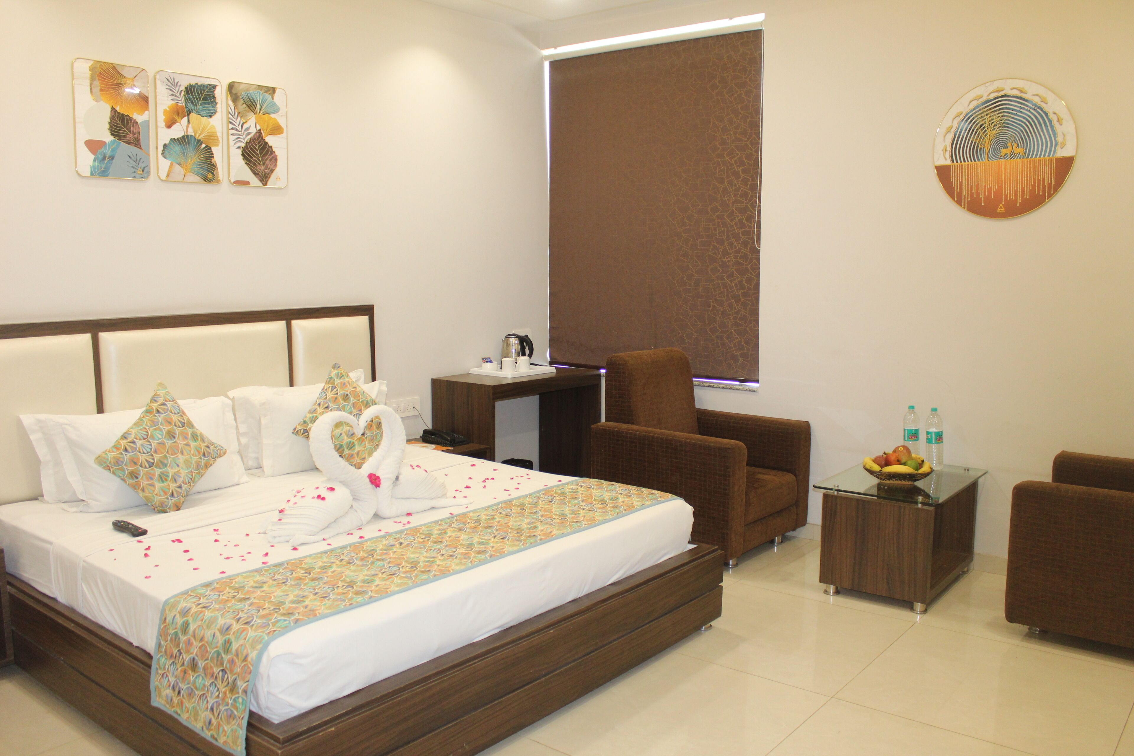 Habitación de hotel con una cama, dos sillones marrones, una mesita con frutero y un escritorio con lámpara.