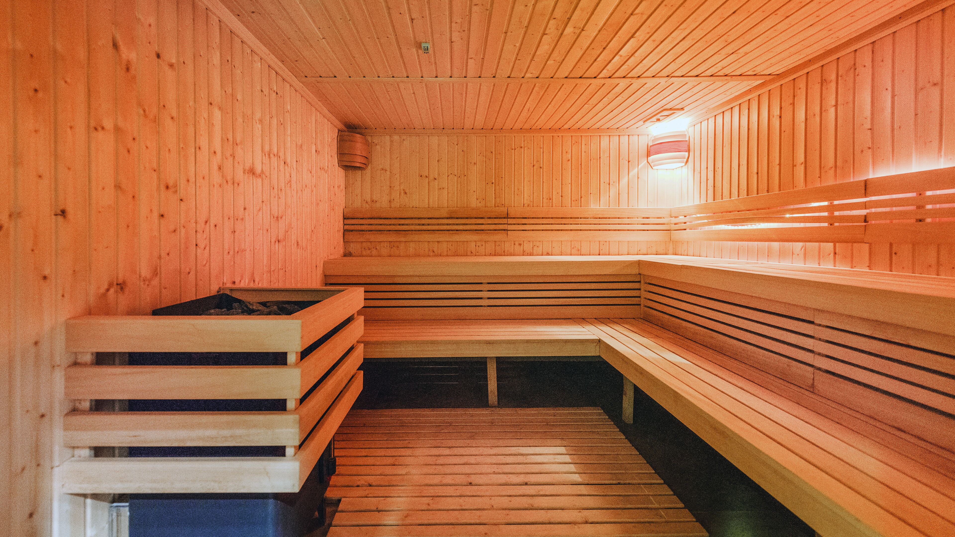A sauna with wooden benches and a sloped floor.