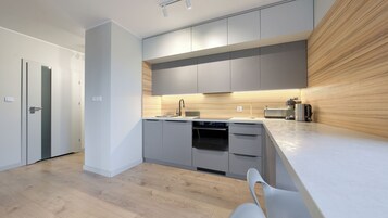 Una cocina moderna con armarios grises, una pared de acento de madera y una encimera blanca.