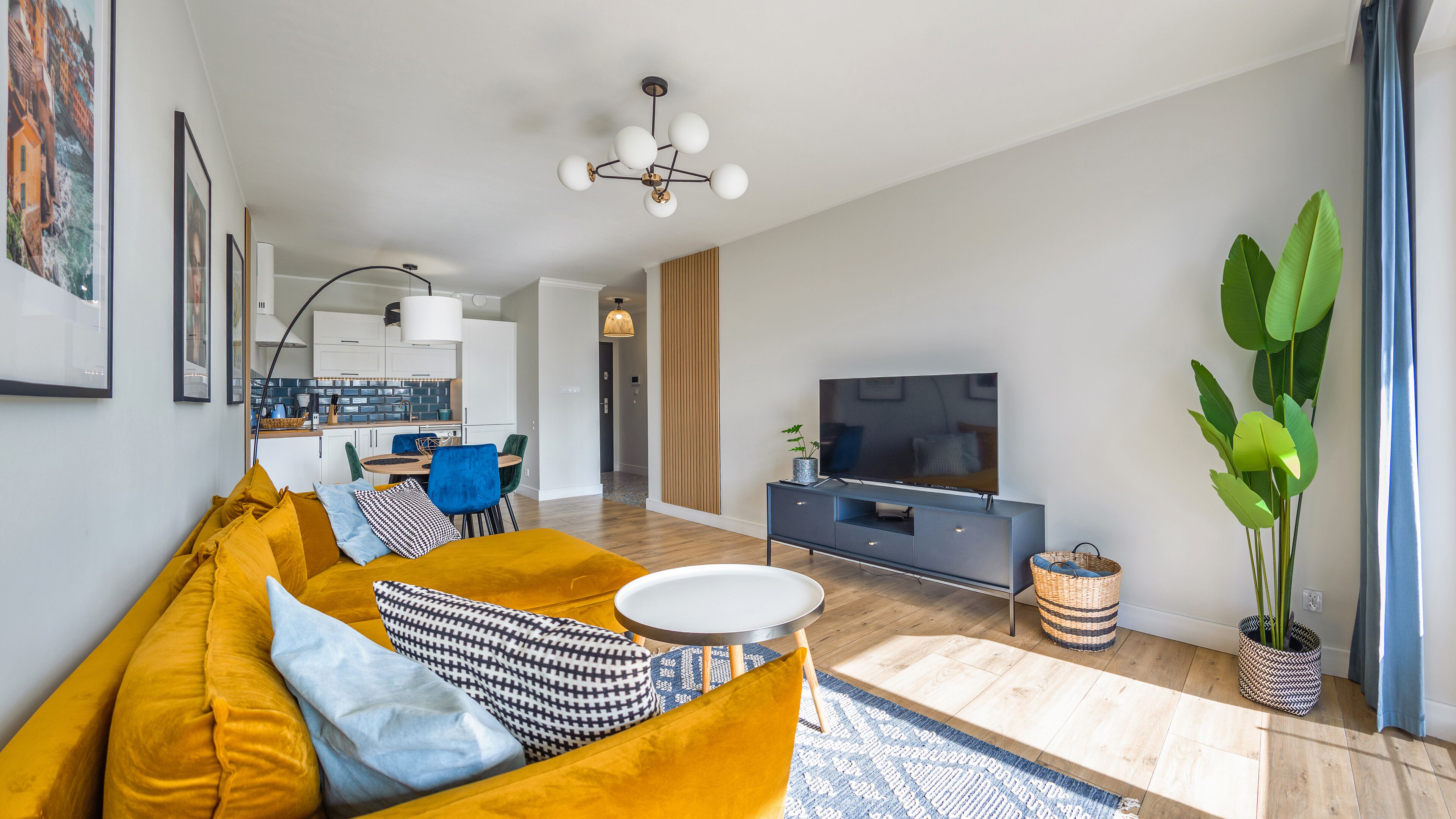 A modern living room with a sofa, TV, and dining area.