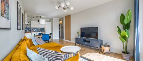 A modern living room with a sofa, TV, and dining area.