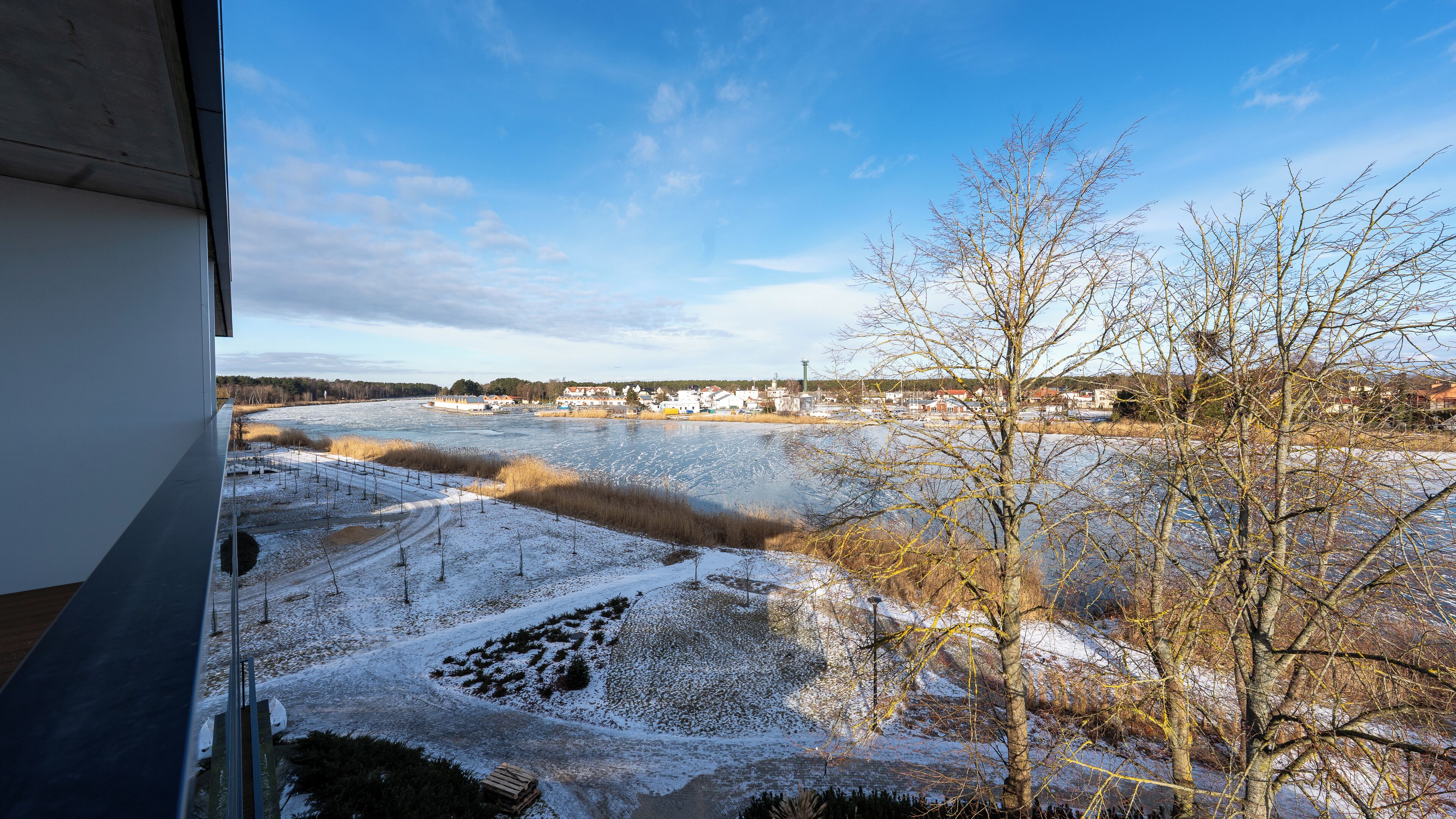 Blick aus einem Fenster auf einen Fluss mit schneebedeckten Ufern und eine Stadt in der Ferne.