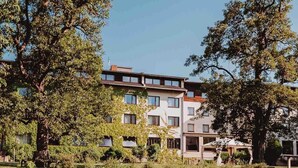 Ein mehrstöckiges Gebäude mit einem Garten im Vordergrund und blauem, wolkenlosem Himmel.
