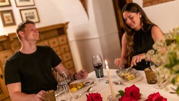 A dining table with wine glasses, a candle, and red roses.