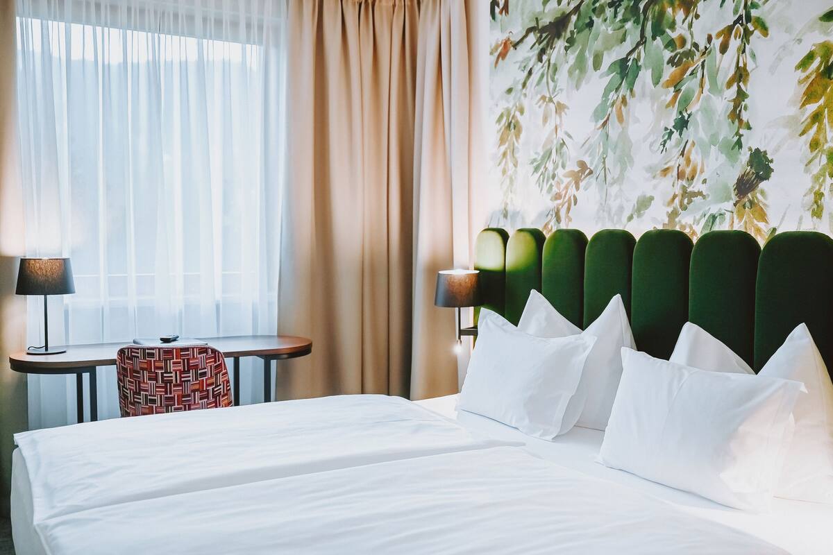 Ein Hotelzimmer mit Bett, Schreibtisch, Stuhl und Lampe.