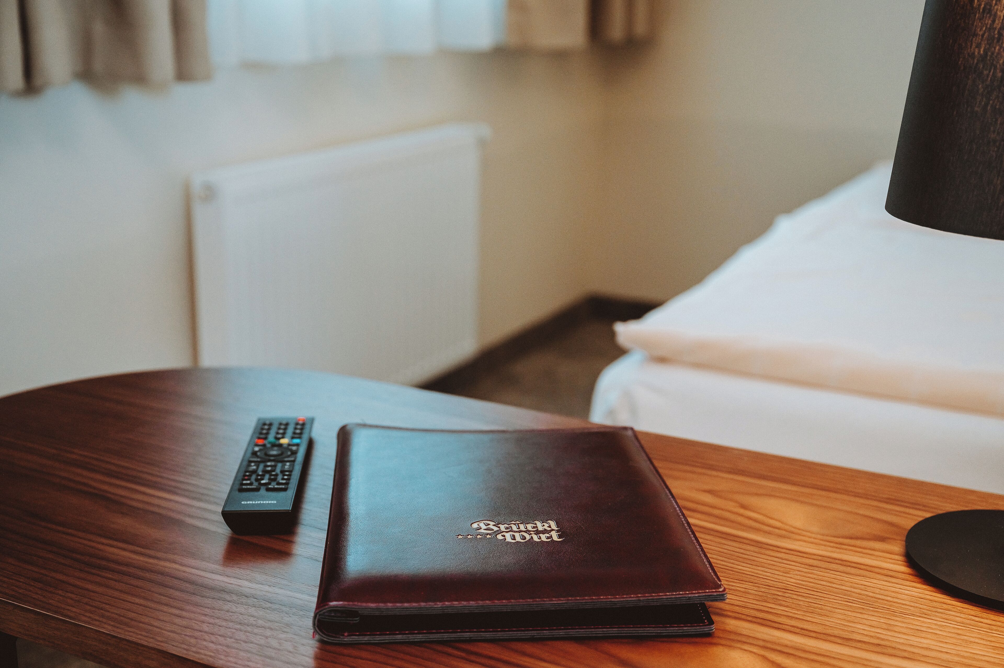 A wooden table with a remote control and a leather wallet on it.
