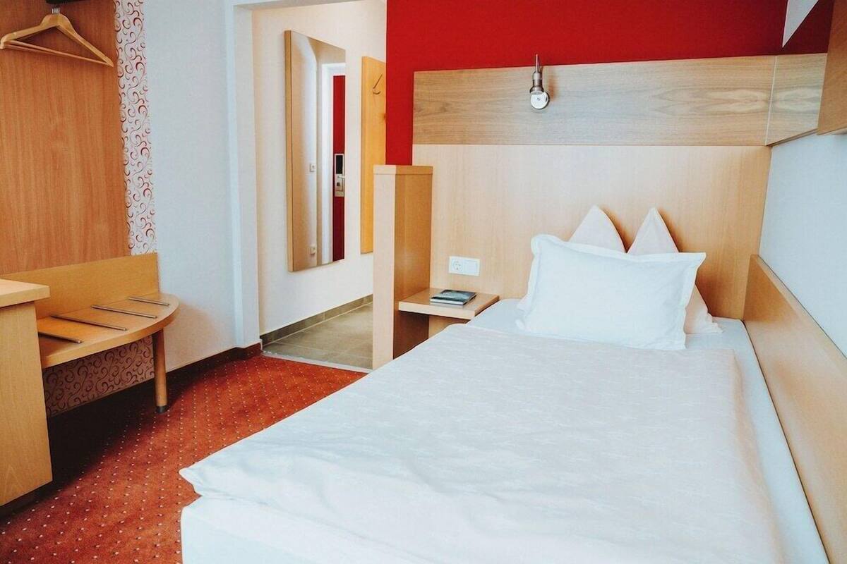 Ein Hotelzimmer mit Bett, Nachttisch und Spiegel.