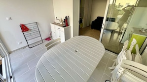 A modern room with a white table, a red bag on a rack, a white cabinet, and a sliding glass door leading to another room.