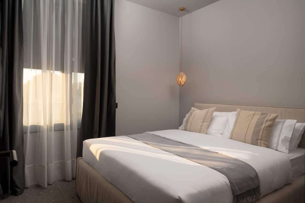 A neatly made bed with a headboard, a bedside table, and a wall-mounted light fixture.