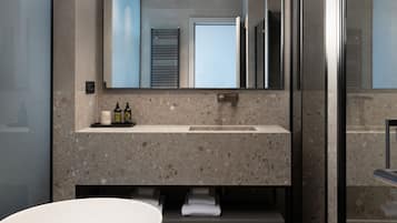A modern bathroom with a large bathtub, a granite countertop vanity, and a large mirror above the sink.