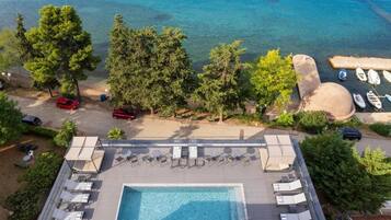 Vista aerea di un resort con piscina, spiaggia e imbarcazioni.