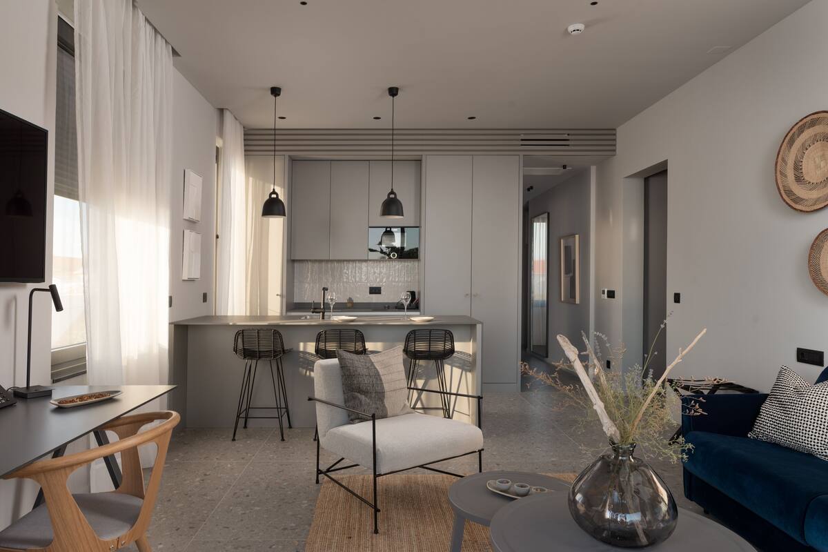 A modern living room with a sofa, a coffee table, and a dining area with a bar.