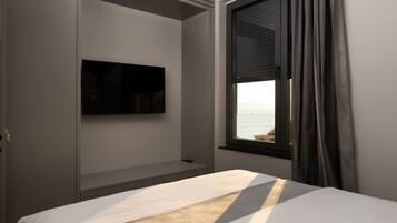 A hotel room with a bed, a mounted TV, a window with curtains, and a view of the sea.